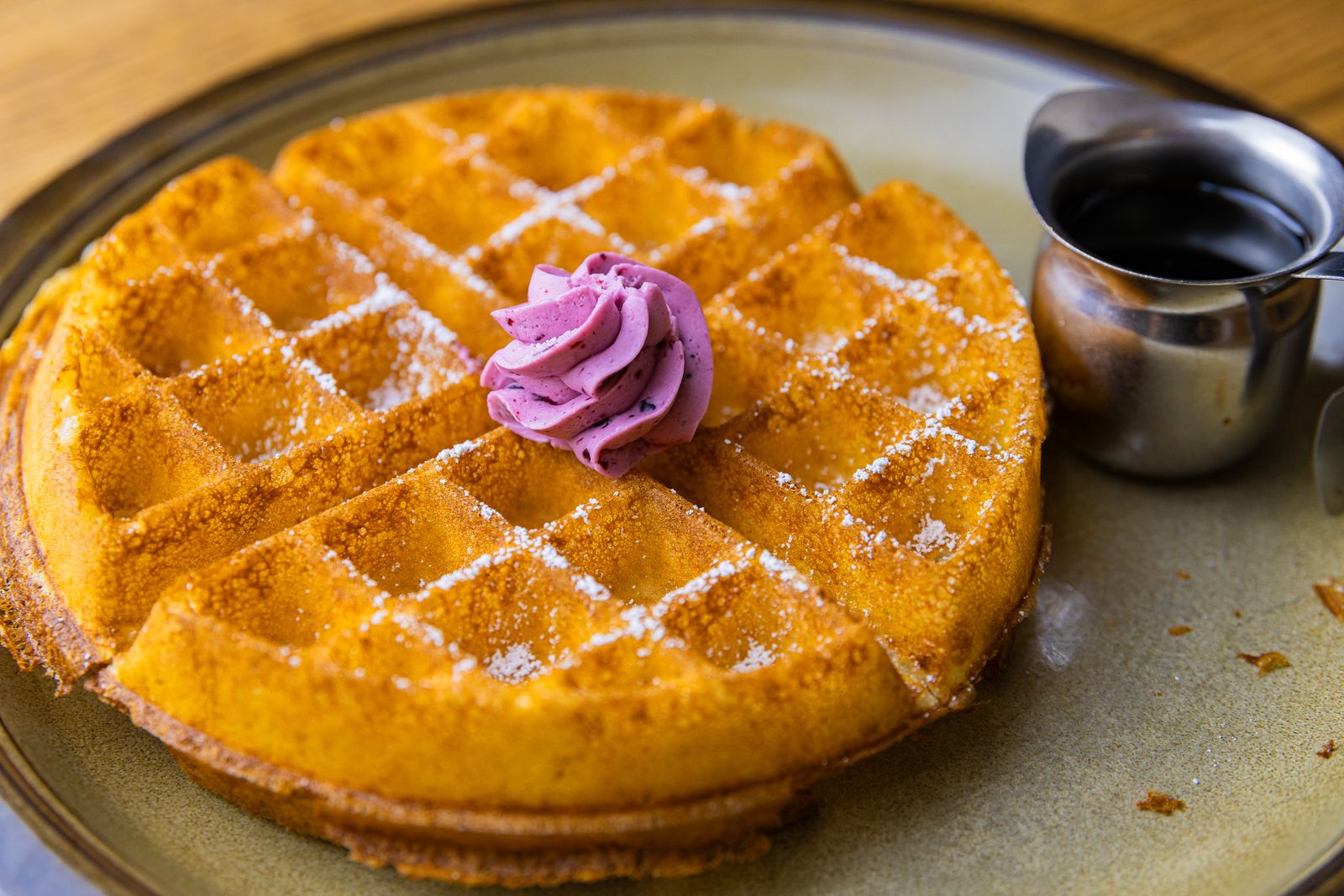 A Belgian waffle topped with whipped cream and powdered sugar.