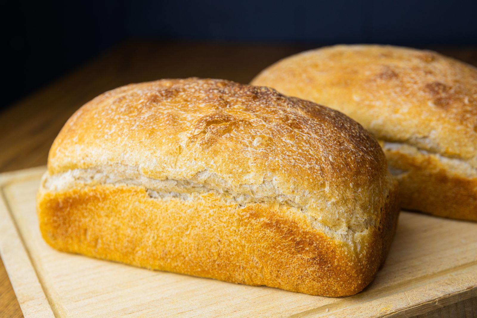 Two loaves of golden house-made sourdough bread on a cutting board.