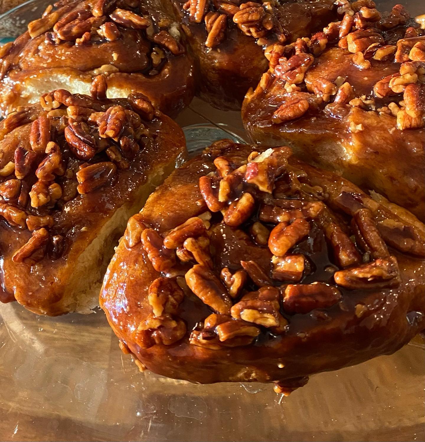 A tray of freshly baked pecan sticky buns glazed and topped with chopped pecans.